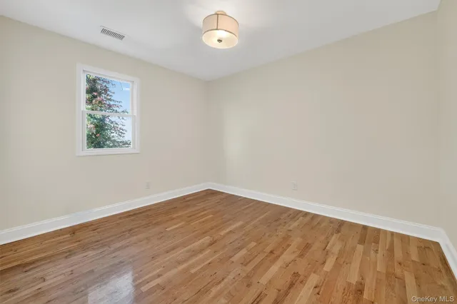 an empty room with wooden floor and a window