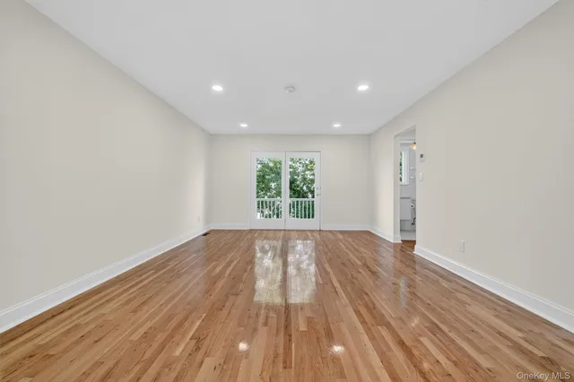 a view of an empty room with wooden floor and window