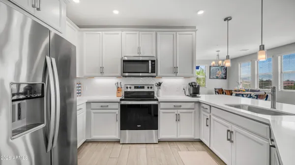 a kitchen with white cabinets stainless steel appliances and a refrigerator