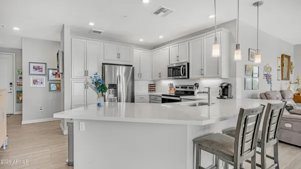 a kitchen with stainless steel appliances a refrigerator a stove a sink a dining table and chairs