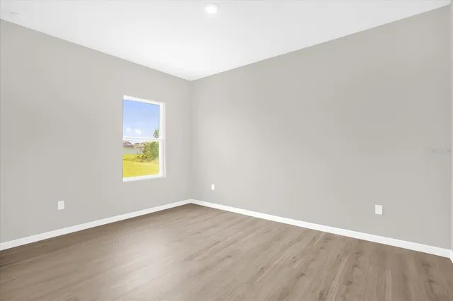 a view of an empty room with a window and wooden floor