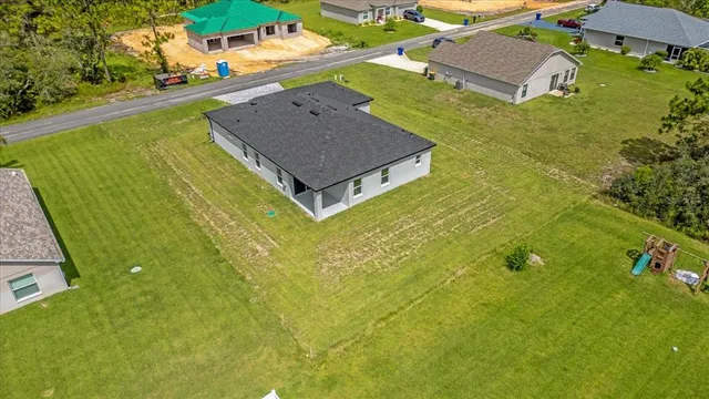 an aerial view of residential houses with outdoor space and trees