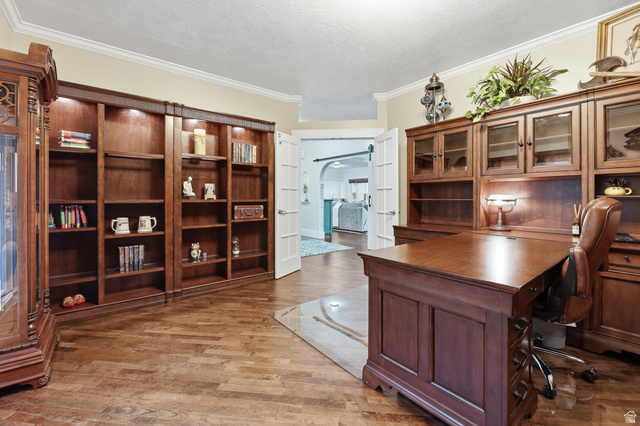 2342 Charros Road Sandy, UT 84092 - Photo 11 of 94 Dedicated office space featuring rich wood-finish flooring, built-in shelving with integrated lighting, extensive built-in cabinetry, and crown molding
