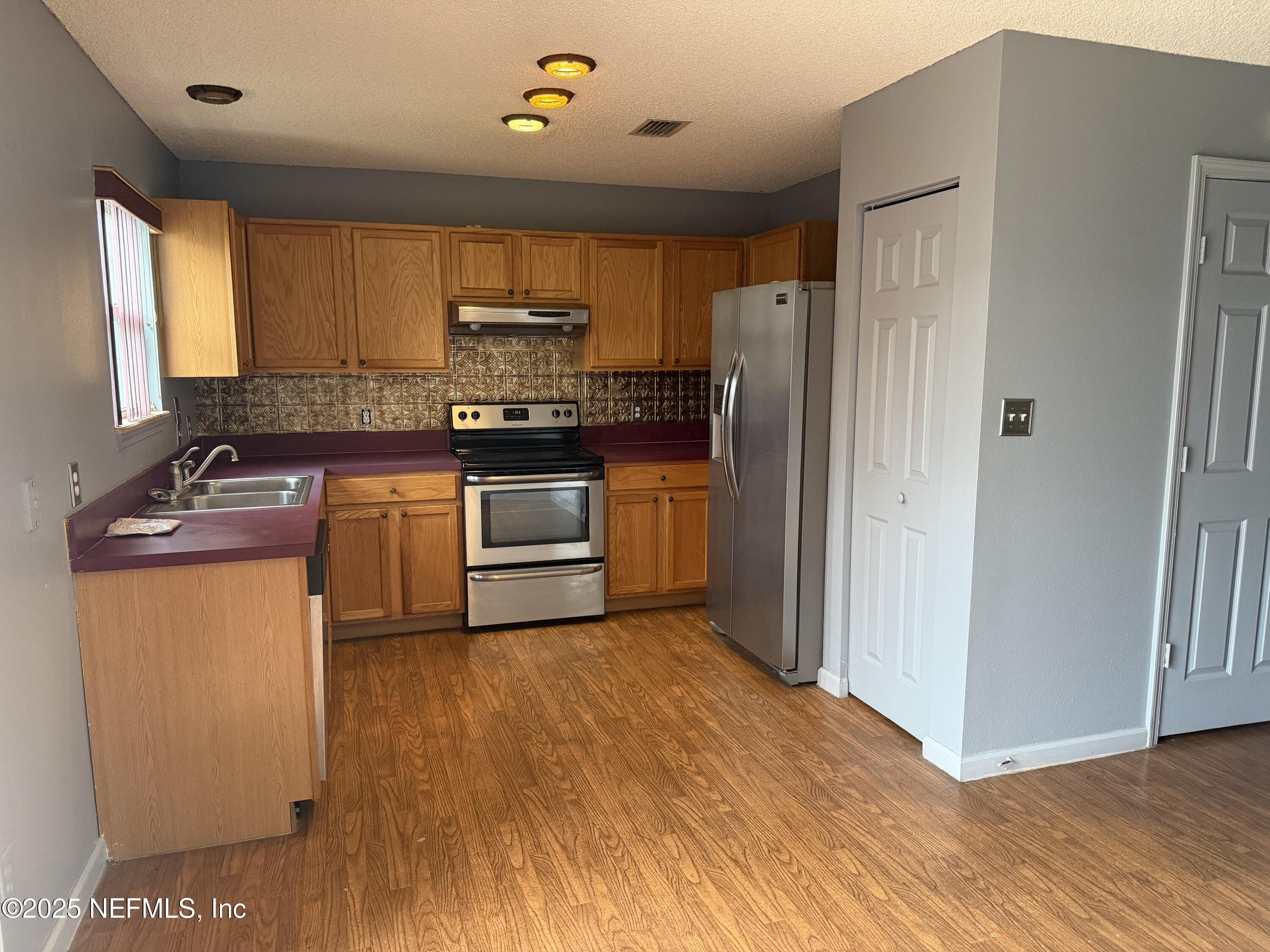 1114 Scheidel Court Atlantic Beach, FL 32233 - Photo 3 of 13 a kitchen with stainless steel appliances granite countertop a refrigerator a stove top oven a sink and dishwasher