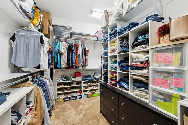 a view of walk in closet with clothes and shoes