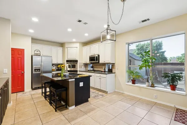 a kitchen with kitchen island granite countertop a refrigerator a stove top oven a sink dishwasher and wooden cabinets