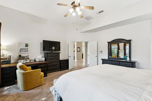 a bedroom with a bed a dresser and flat screen tv