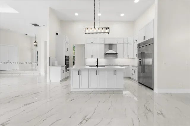 a large white kitchen with cabinets and a refrigerator