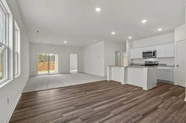 a room with kitchen island a sink wooden floor and stainless steel appliances
