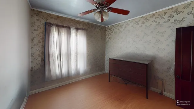 a view of an empty room with window and chandelier fan