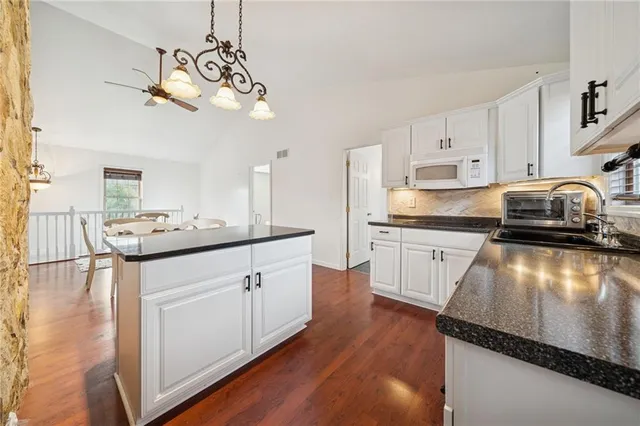 a kitchen with granite countertop a sink cabinets stainless steel appliances and a window