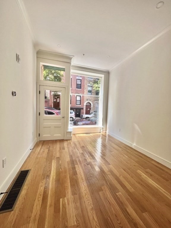 18 Grove Street, Unit 1 Boston, MA 02114 - Photo 3 of 13 an empty room with wooden floor and windows