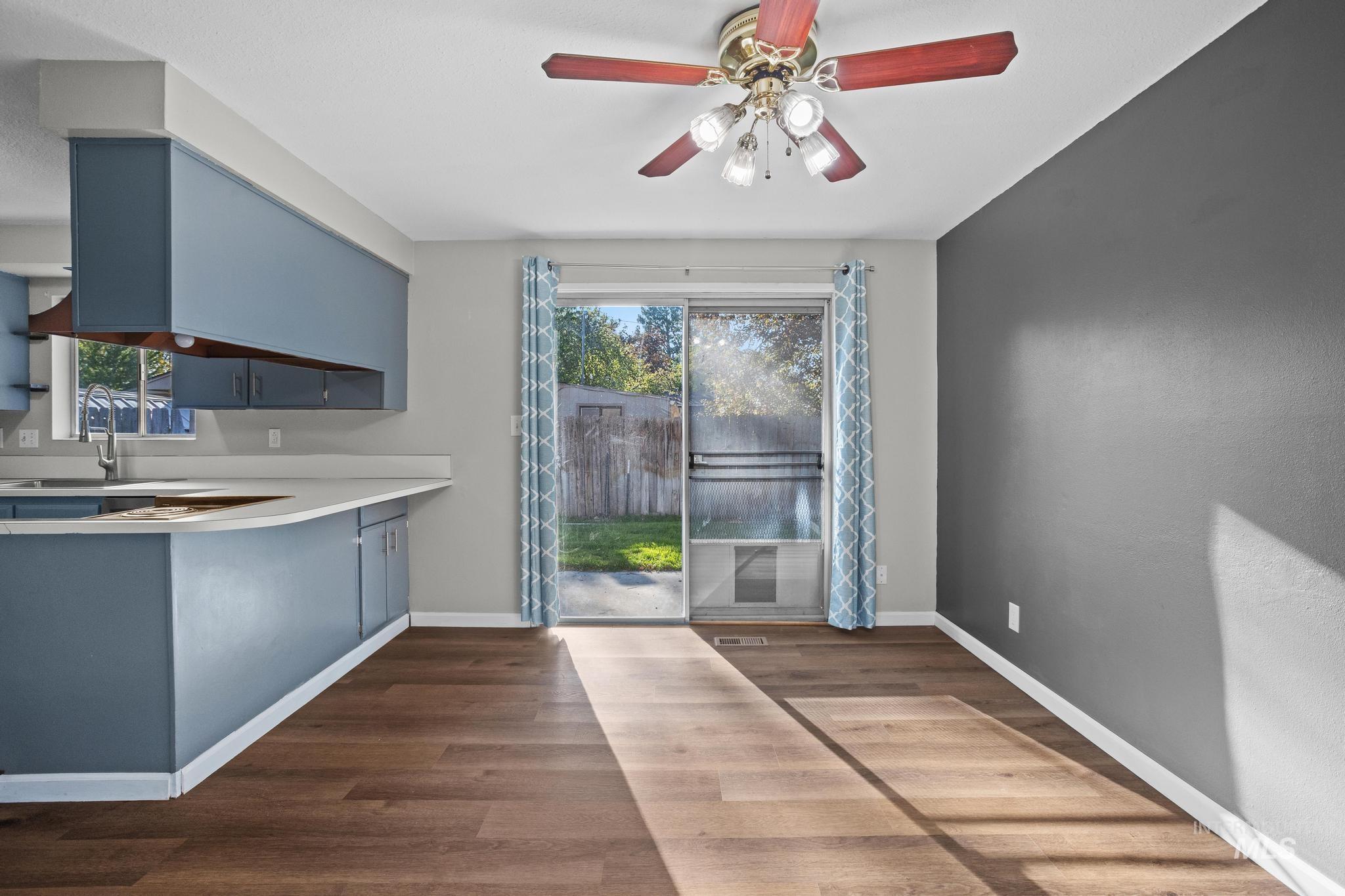 2037 South Curtis Road Boise, ID 83705 - Photo 10 of 32 Wood-finish flooring, sliding glass door, overhead lighting with ceiling fan, kitchen cabinetry with integrated sink, and light-toned countertops