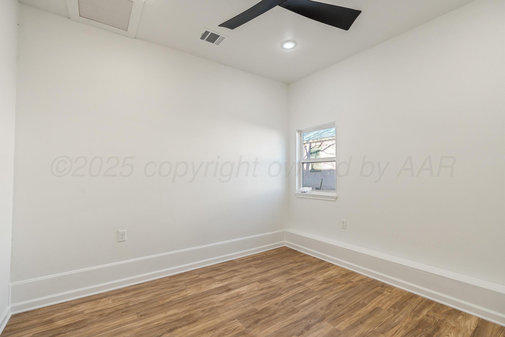 220 Sims Street Clarendon, TX 79226 - Photo 13 of 17 an empty room with wooden floor and windows