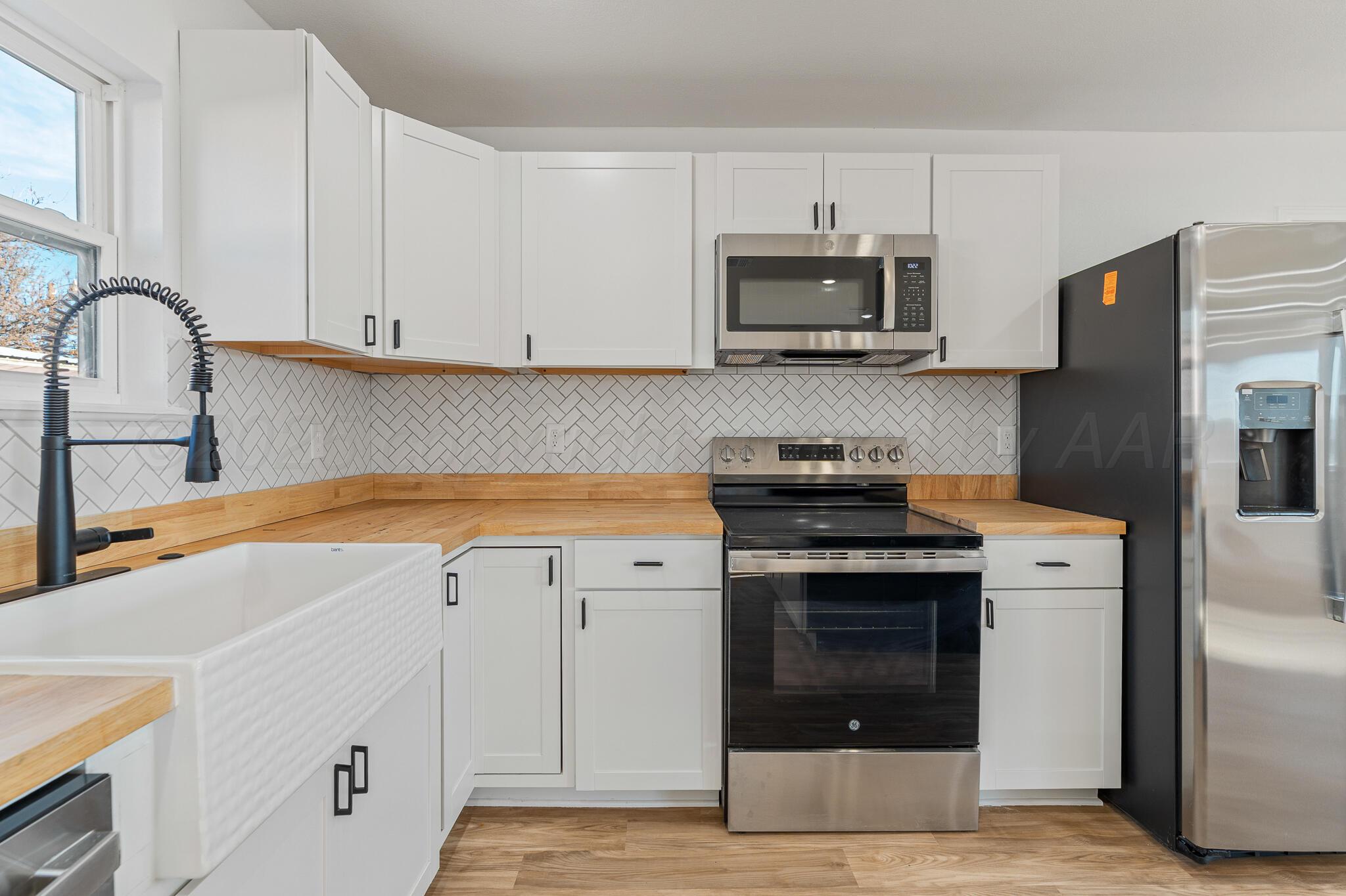 220 Sims Street Clarendon, TX 79226 - Photo 6 of 17 a kitchen with stainless steel appliances a stove a sink and a microwave