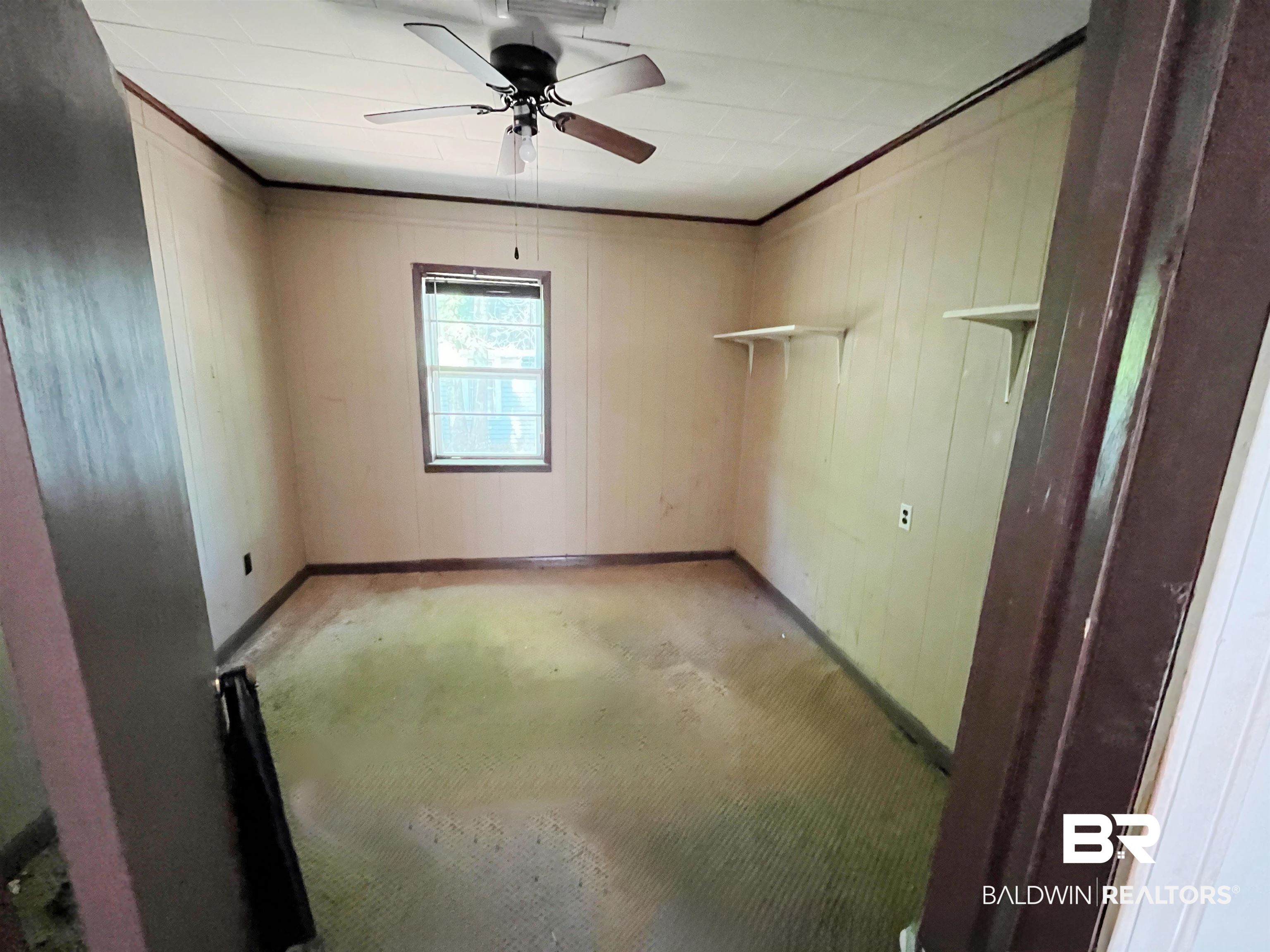 215 Adams Street Atmore, AL 36502 - Photo 5 of 7 Unfurnished room with a ceiling fan and wood walls