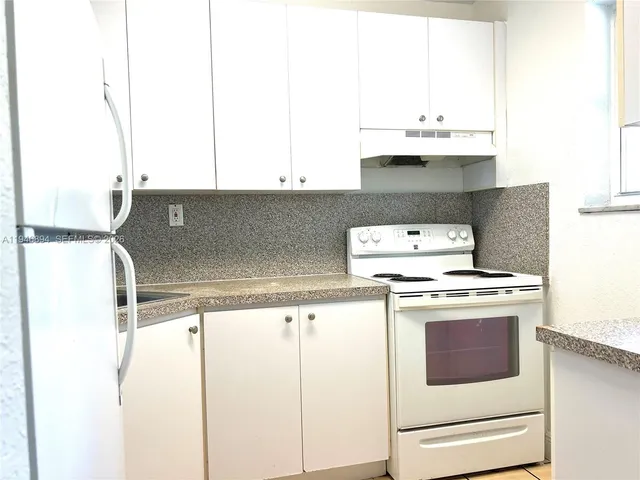 a kitchen with a sink a stove and white cabinets