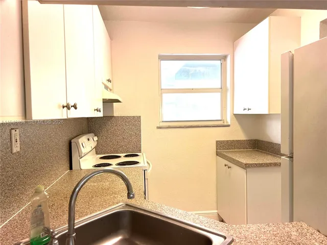 a view of a kitchen with a sink and a refrigerator