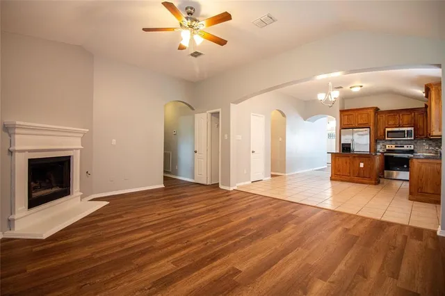 a view of a livingroom with a fireplace a ceiling fan and wooden floor