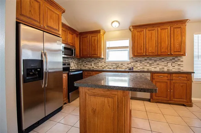 a kitchen with granite countertop a refrigerator and cabinets