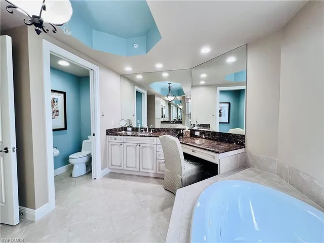 a large white kitchen with a white countertops a stove a dining table and chairs