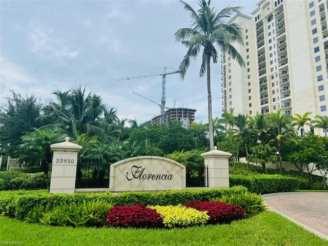 a view of sign board with flower plants and wooden fence