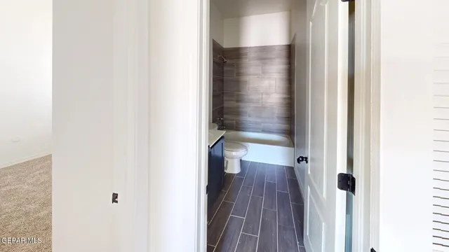 a view of a hallway with wooden floor and a bathroom