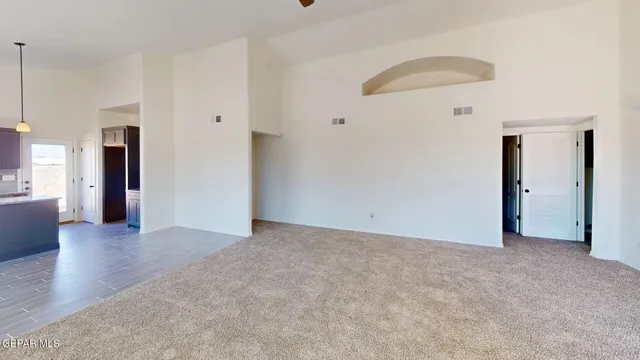 a view of an empty room with wooden floor and a kitchen