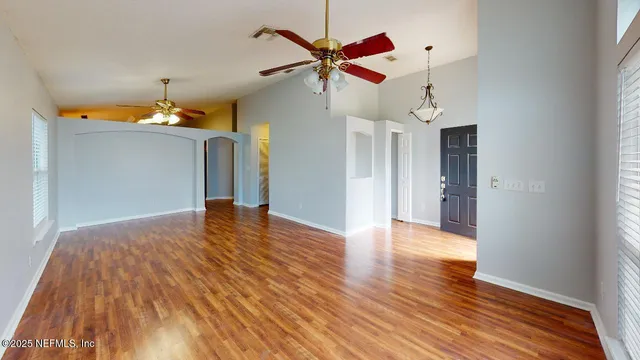 a view of a livingroom with a ceiling fan wooden floor and a ceiling fan