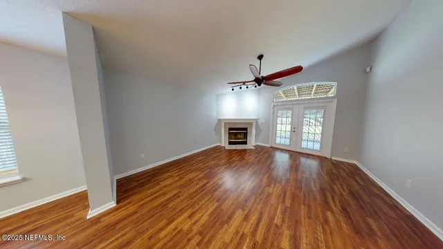 a view of empty room with wooden floor and fan