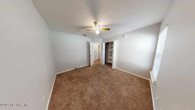 an empty room with closet and a chandelier fan