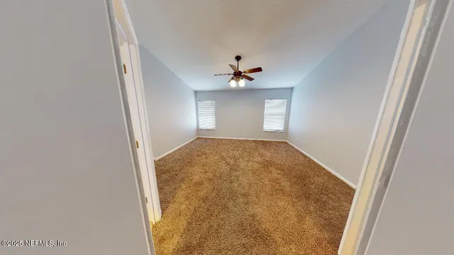an empty room with a ceiling fan and carpet