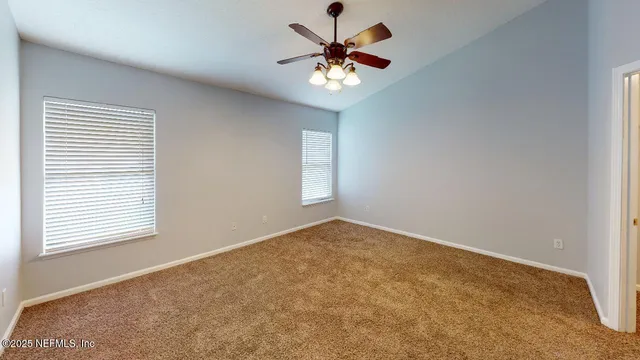 an empty room that has a chandelier fan and a window