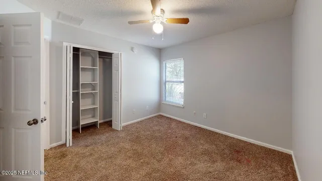an empty room with closet and a chandelier fan