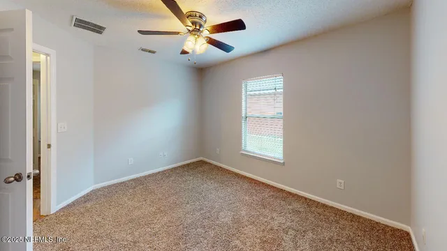 an empty room with windows and fan