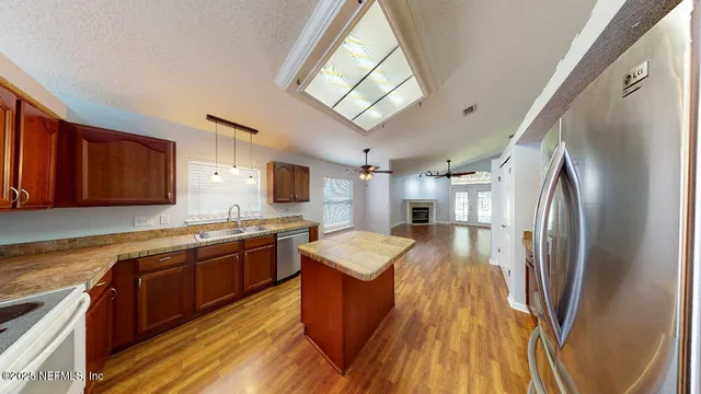 a large kitchen with stainless steel appliances granite countertop a refrigerator a sink dishwasher a stove and white countertops with wooden floor