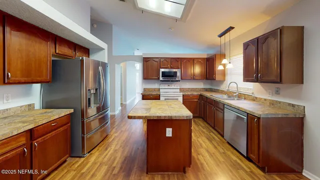 a kitchen with stainless steel appliances granite countertop wooden floor sink stove and refrigerator