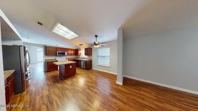 a kitchen with stainless steel appliances a refrigerator and wooden floor