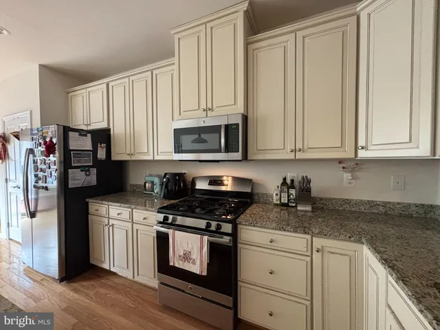 a kitchen with granite countertop white cabinets and stainless steel appliances