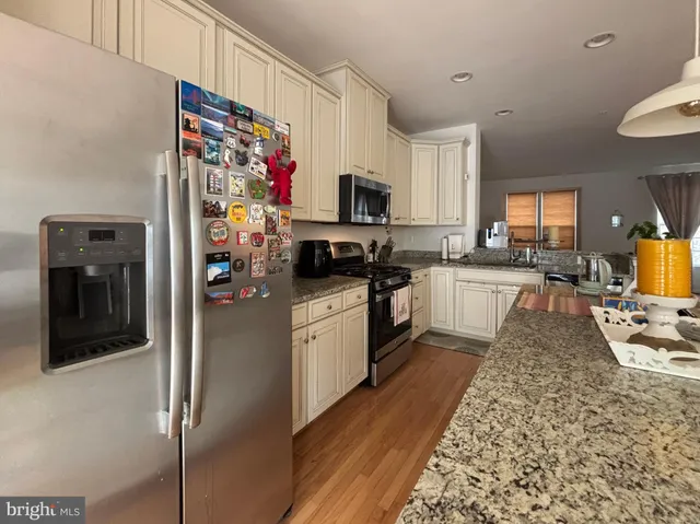 a kitchen with stainless steel appliances granite countertop a refrigerator sink and stove