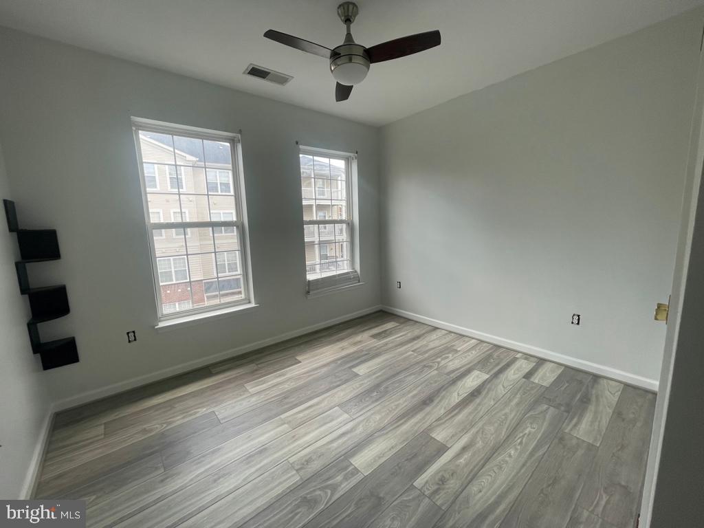 9713 Handerson Place, Unit 304 Manassas Park, VA 20111 - Photo 6 of 14 a view of an empty room with a window and wooden floor