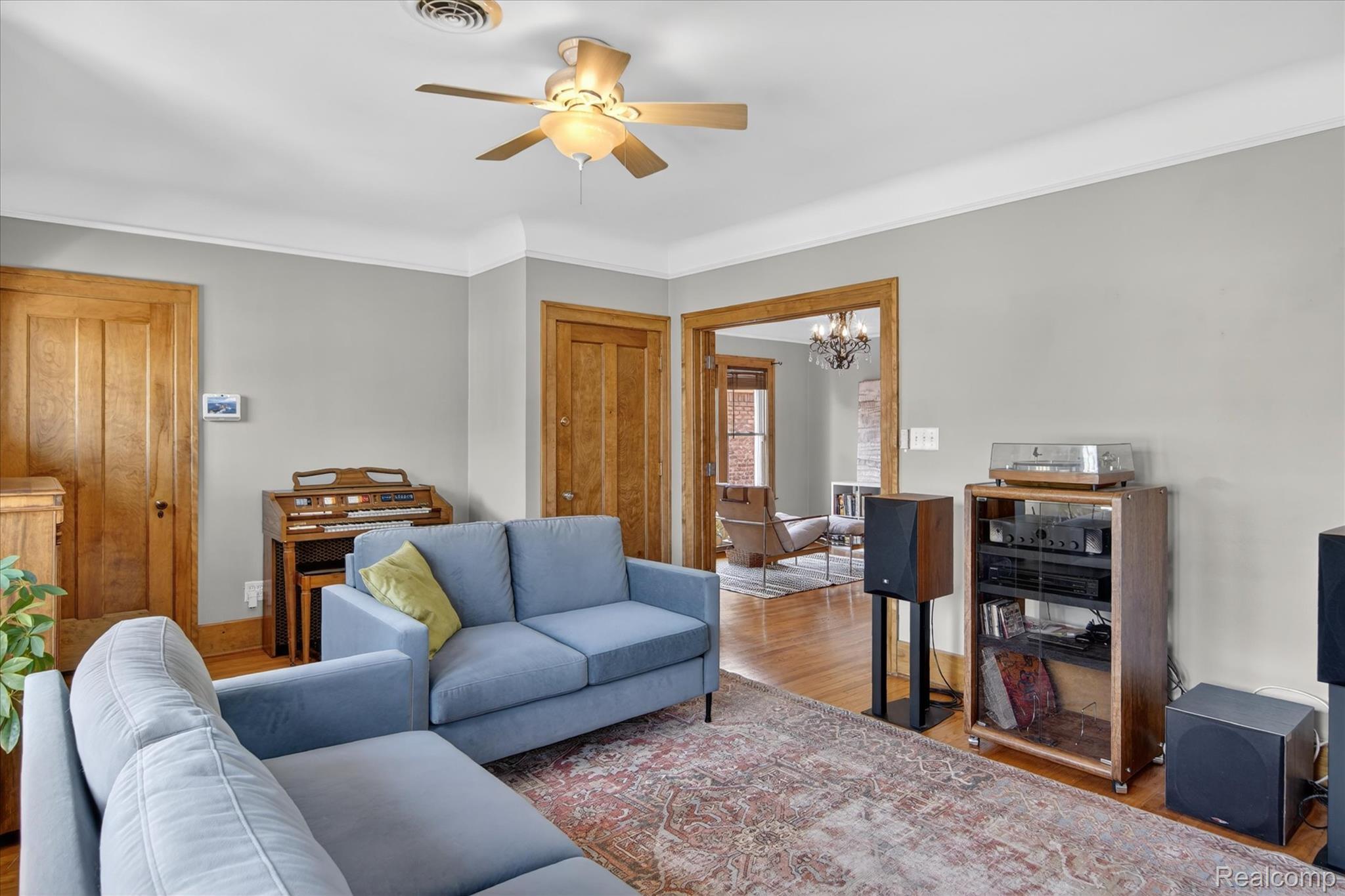 925 Nottingham Road Grosse Pointe, MI 48230 - Photo 3 of 46 Living room featuring suspended lighting, a ceiling fan, wood finished floors, and crown molding