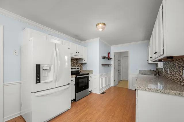 a kitchen with granite countertop white cabinets and white appliances