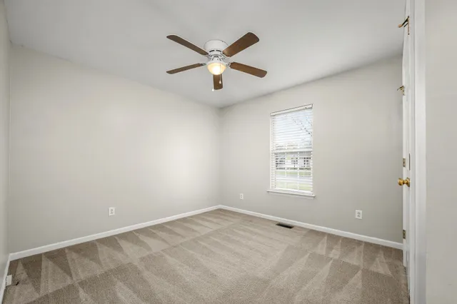 an empty room with closet and a chandelier fan