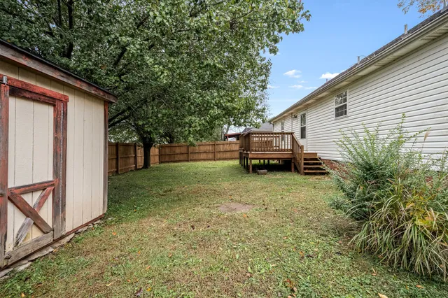 a view of backyard with large trees and wooden fence