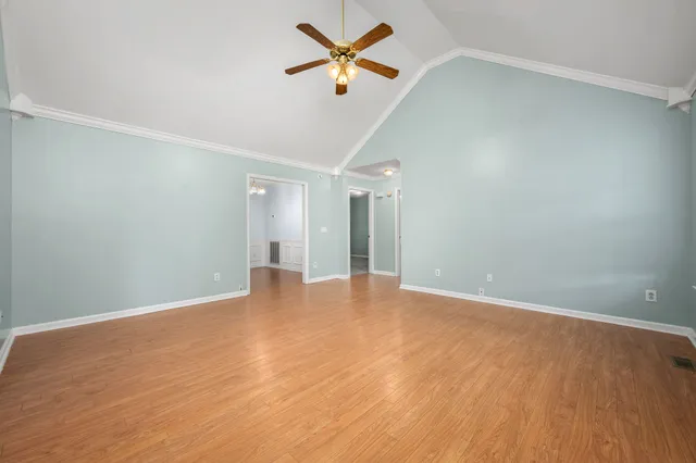 an empty room with wooden floor ceiling fan and window
