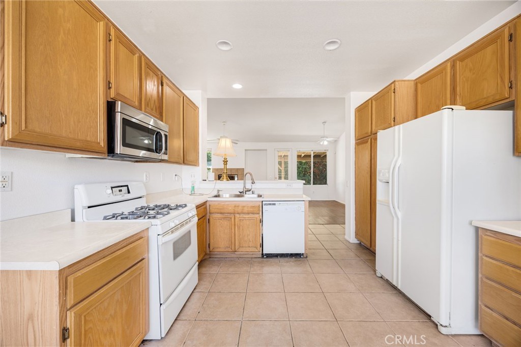 4546 Spring Court Banning, CA 92220 - Photo 5 of 17 a kitchen with a refrigerator a stove top oven a sink dishwasher and wooden cabinets