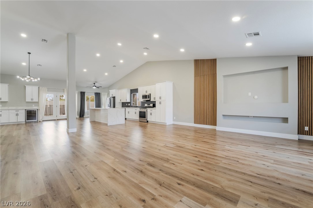 9171 West Viking Road Las Vegas, NV 89147 - Photo 7 of 43 An open concept living space features high ceilings, contemporary lighting, and a modern kitchen with a large island.