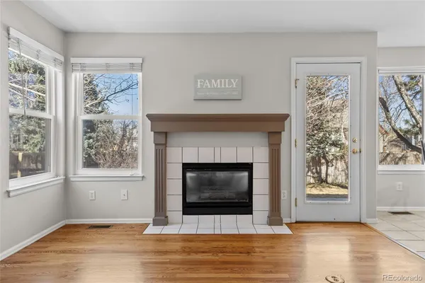 an empty room with wooden floor fireplace and a window