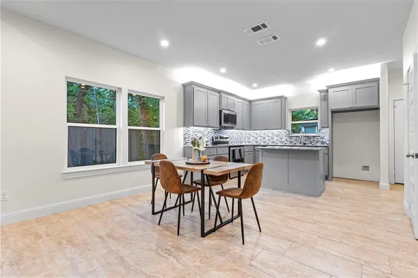 a dining hall with stainless steel appliances granite countertop a dining table chairs and window